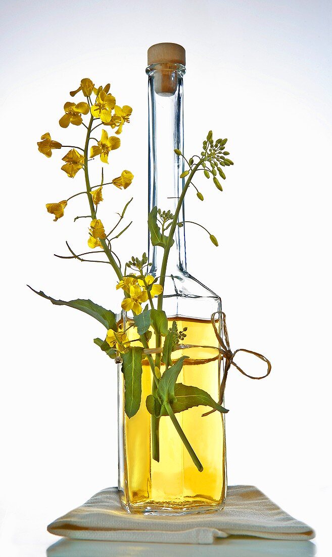 Half-filled bottle of rapeseed oil with flowers