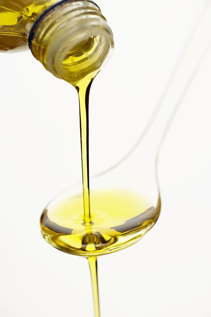 Olivenöl über einen Löffel gießen