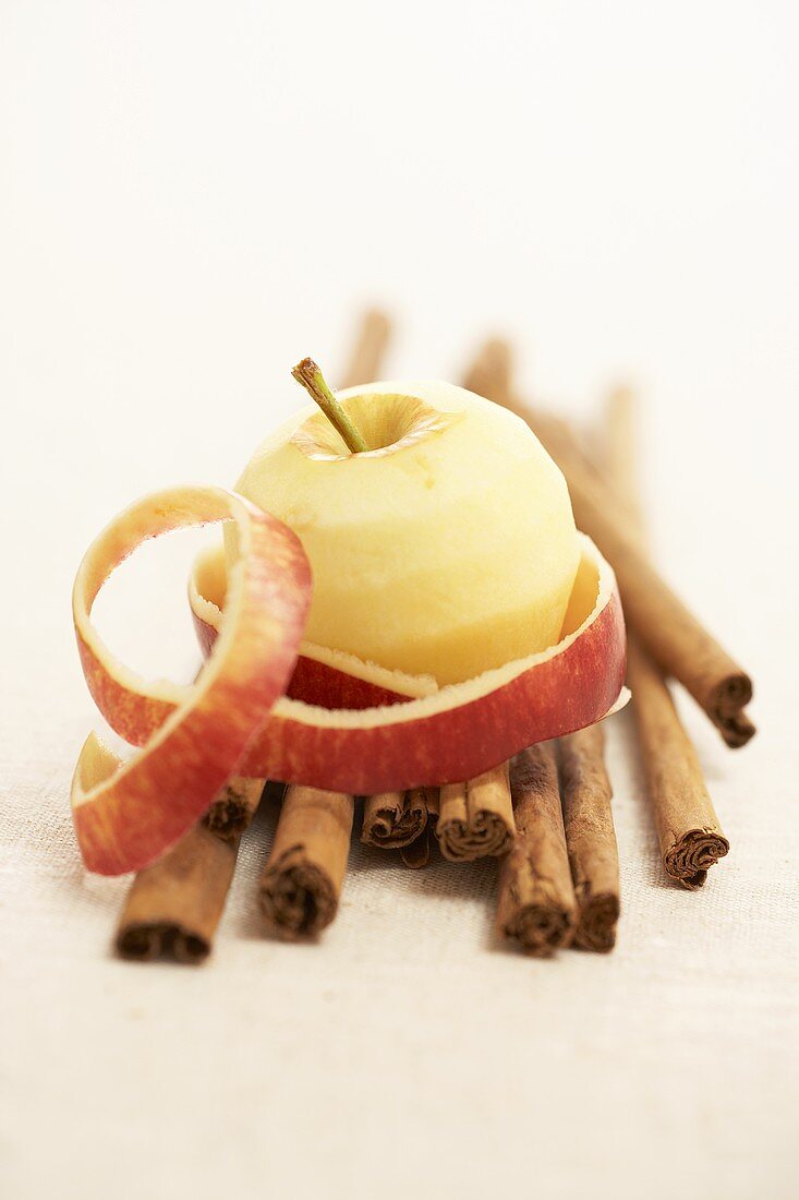 A peeled apple on cinnamon sticks