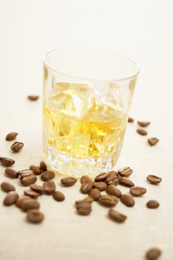 A glass of whisky with ice and coffee beans