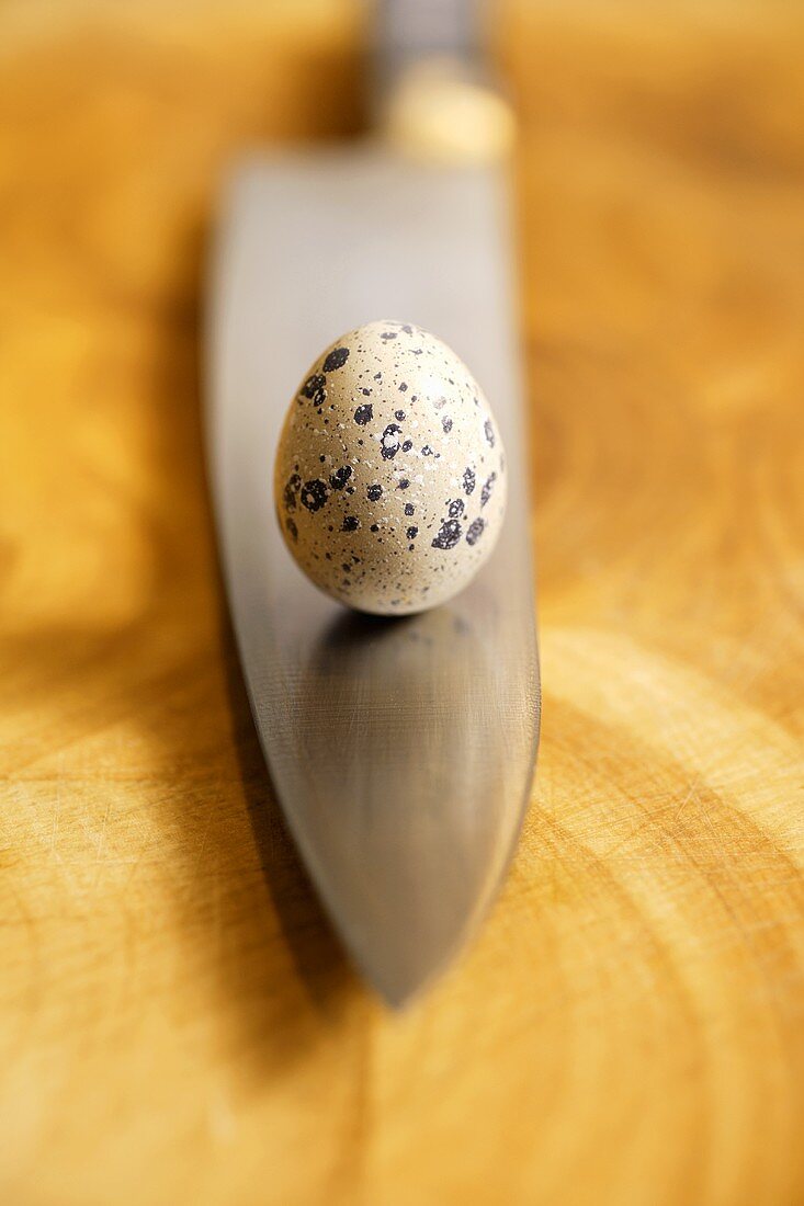 A quail's egg standing on a knife