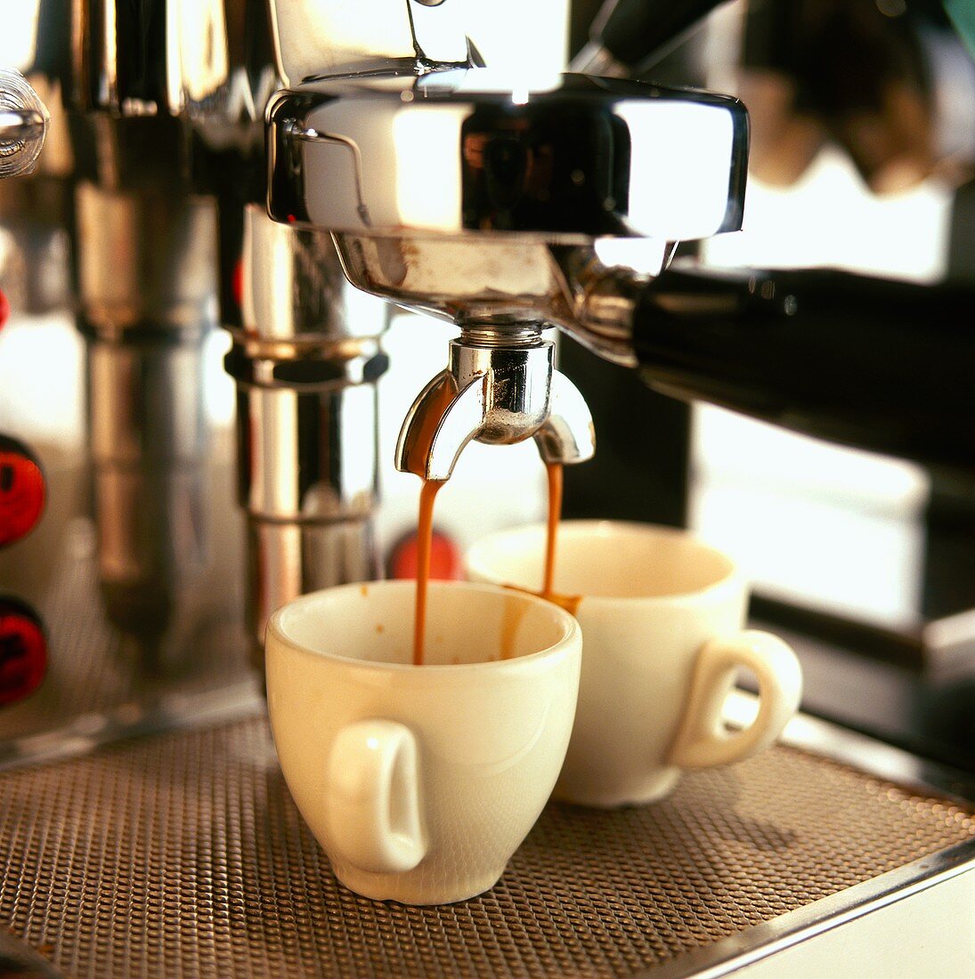 Espresso fliesst aus der Espressomaschine in zwei Tassen