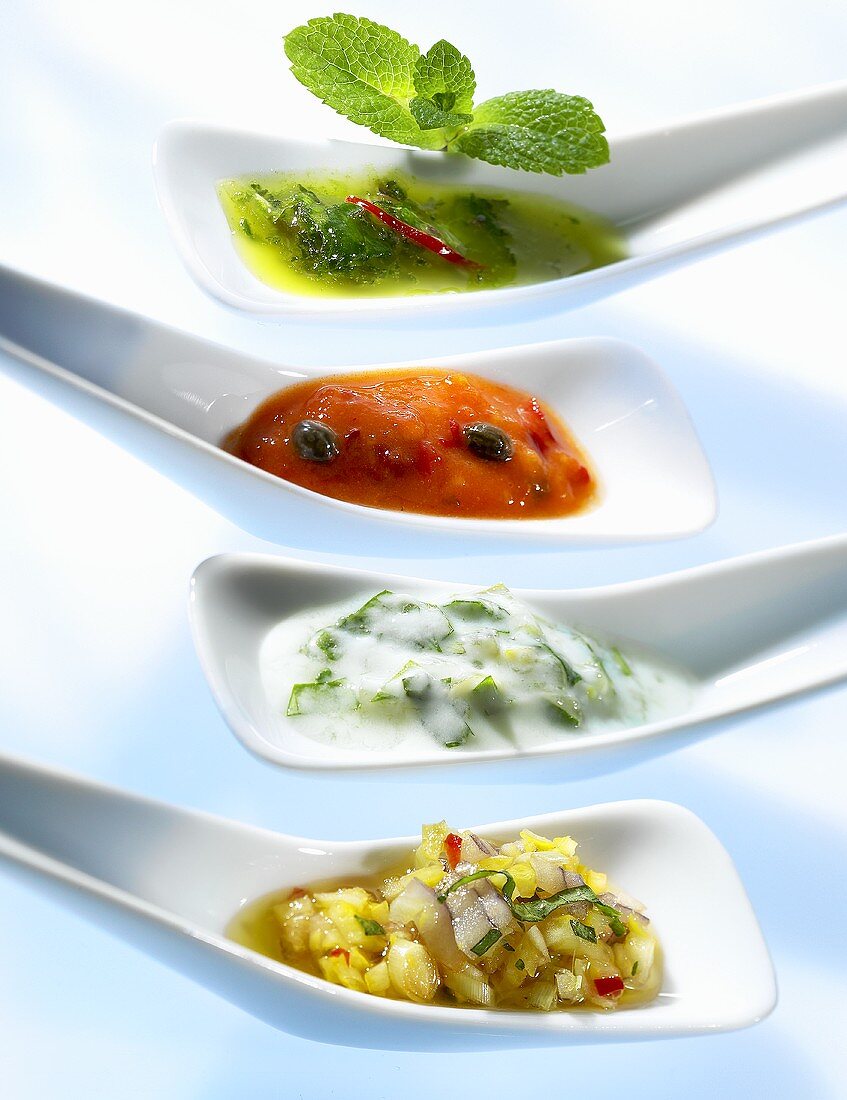 Four chutneys and relishes on small spoons