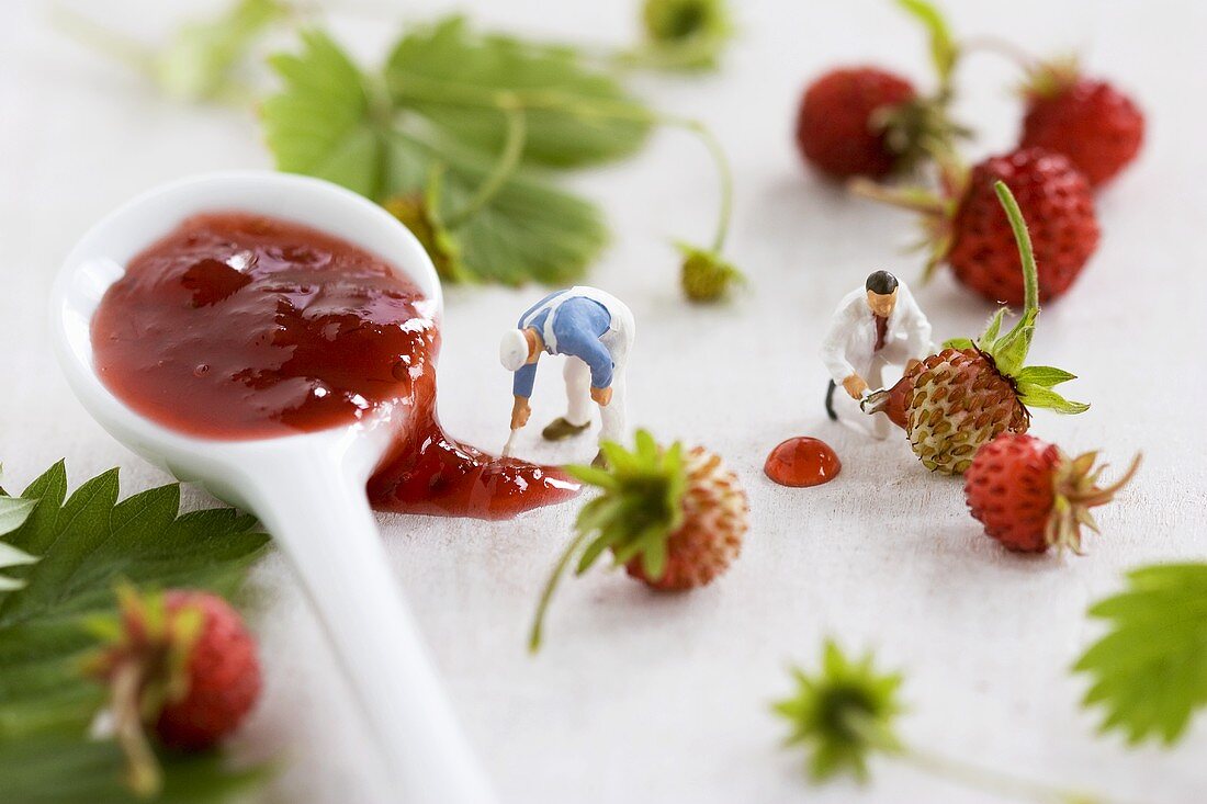 Two little toy men among wild strawberries and jam