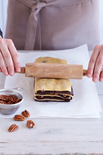Zebra biscuits being made: light and dark pastry being layered with pecan nuts