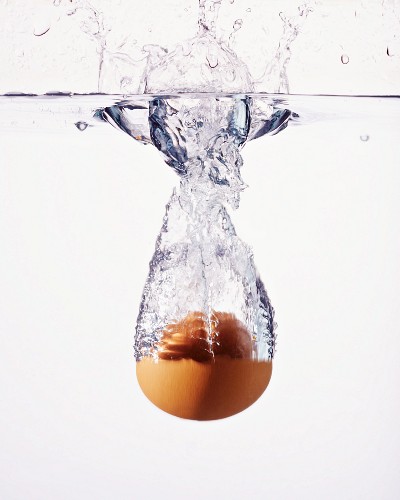 A brown egg falling into water
