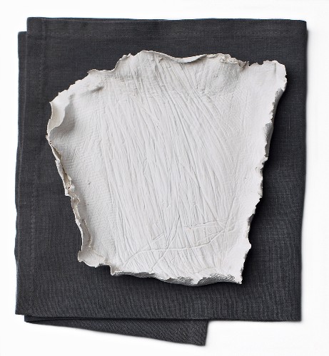 A home-made plate made from modelling clay on a grey cloth