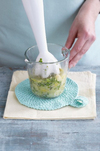 A mixture of vegetables being mixed with a hand blender