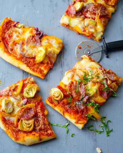 A pizza with vegetables, salami and mozzarella