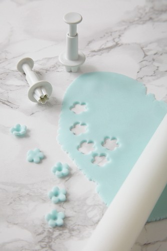 Sugar flowers being cut out of pastel-blue fondant