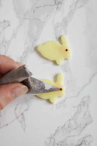 Fondant Easter bunnies being decorated with chocolate glaze