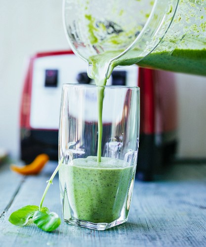 A seaweed and chicory smoothie with hemp seeds, chickweed, basil and parsley being poured into a glass