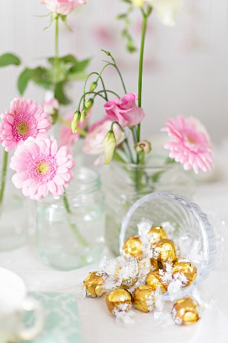 Golden bonbons and pink flowers on a buffet