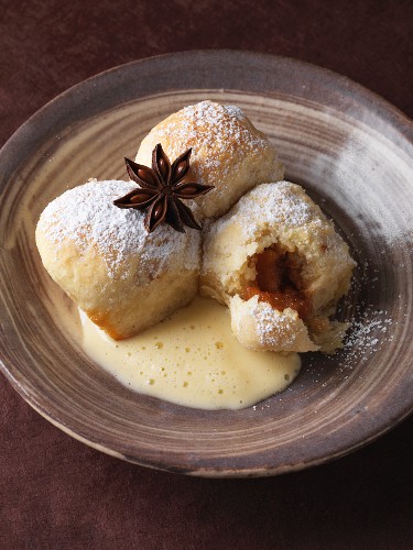 Buchteln (baked, sweet yeast dumplings) filled with preserved pears in a star anise and vanilla sauce