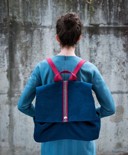 A woman carrying a canvas rucksack on her back