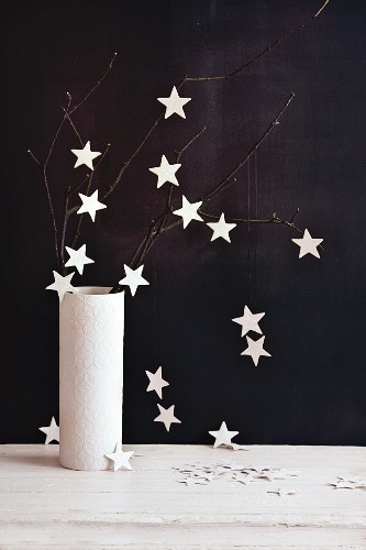 A twig decorated with glittery stars in a vase