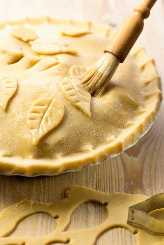 Apple pie being made: lid being decorated with pastry leaves