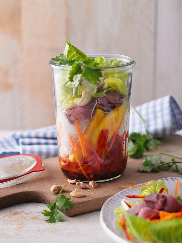 A layered Thai salad with mango and roast beef in a jar