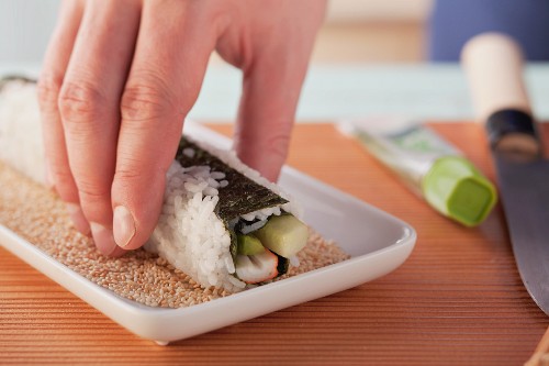 California-Rolls zubereiten: Sushi-Rolle in Sesamsamen wälzen