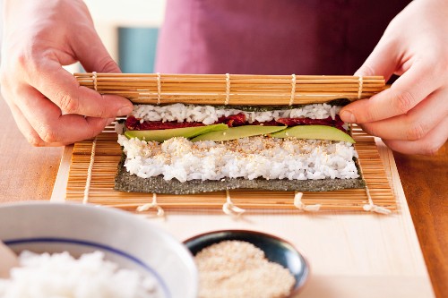 Maki sushi being prepared: a bamboo mat being rolled up