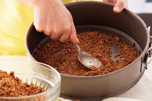 Spreading biscuit mixture on base of a loose-bottomed cake tin