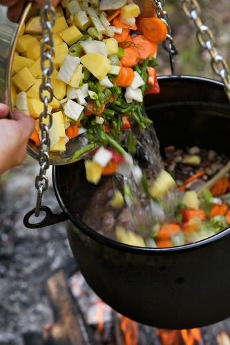Vegetable soup in a cauldron over a camp fire