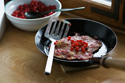 Pancakes with redcurrants in a pan