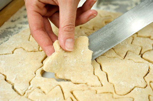 Ausgestochene Mürbteigplätzchen von der Teigplatte lösen