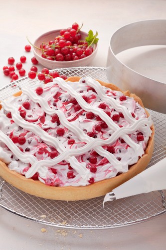 Redcurrant tart with meringue lattice; a cake ring and redcurrants in the background
