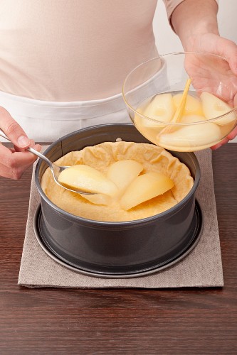 Pear halves being placed in the bottom half of the cake