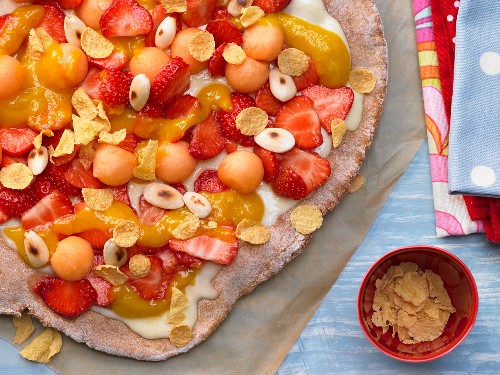 A sweet pizza with fruit, cornflakes and almonds