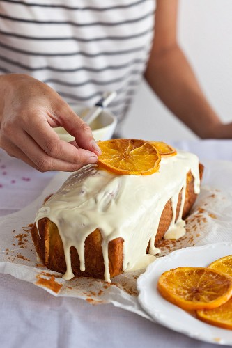 Orange cake being decorated with candied orange slices
