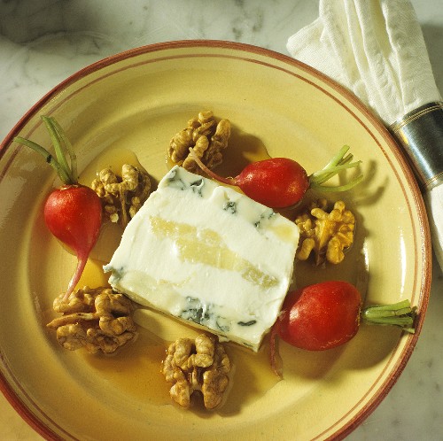 Eine Scheibe Käse-Birnen-Terrine auf Teller mit Walnüssen