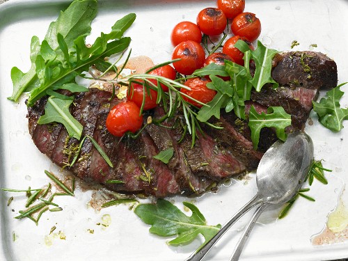 A rump steak with tomatoes and rocket