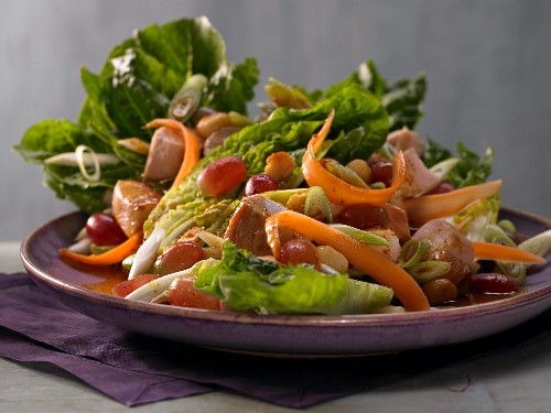 A colourful salad with chicken, grapes, carrot and macadamia nuts