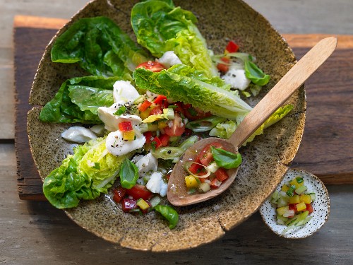 Cod and a vegetable salad with peppers, cucumber, tomatoes and herbs