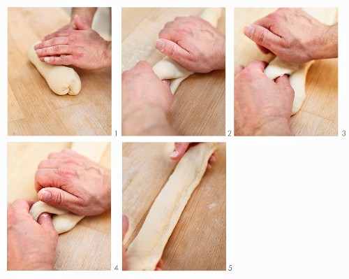 Dough being shaped into white baguettes