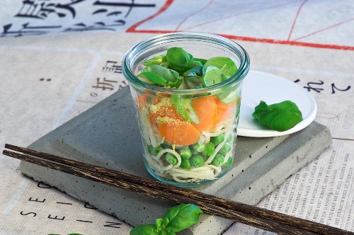 Zutaten für asiatische Nudelsuppe mit Gemüse in Glas geschichtet