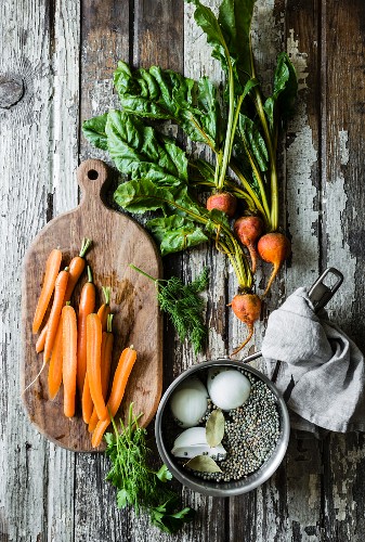 Karotten, Rüben und Linsen auf Vintage-Holztisch (Aufsicht)