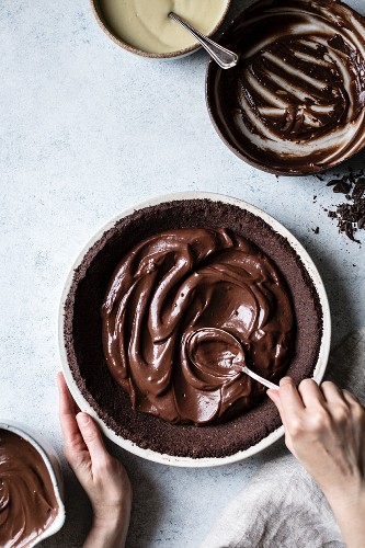 A chocolate pie base being filled with melted chocolate