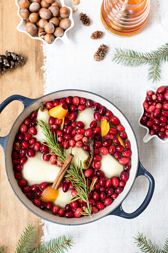 Poached pears with cranberries, cinnamon, rosemary and orange peel in a pot