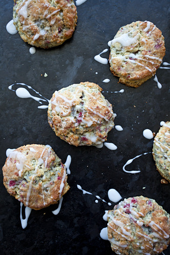 Raspberry scones drizzled with glaze on a black slate surface
