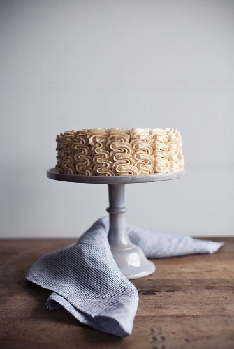 A cream cake with peanut butter cream on a cake stand