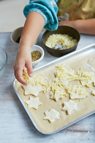 Ungebackene Blätterteigsterne mit Käse bestreuen