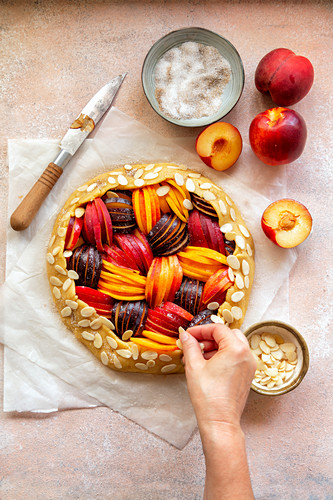 Ungebackene Steinfrucht-Galette mit Mandelblättchen bestreuen