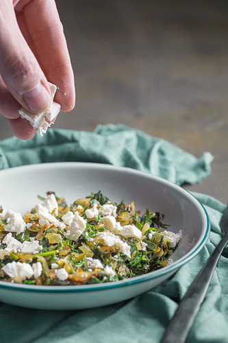 A cook making stuffing for spanakopita (filo pastry with spinach and feta cheese, Greece)