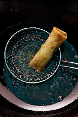 A spring roll in a draining spoon