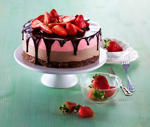 Layer cake with chocolate and strawberry cream, chocolate ganache, and fresh strawberries