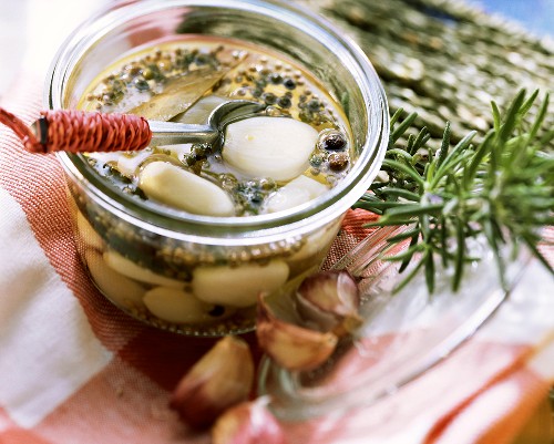 Pickled garlic in pickling jar; sprig of rosemary