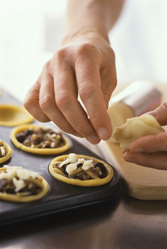 Putting pieces of marzipan on top of mincemeat tarts 
